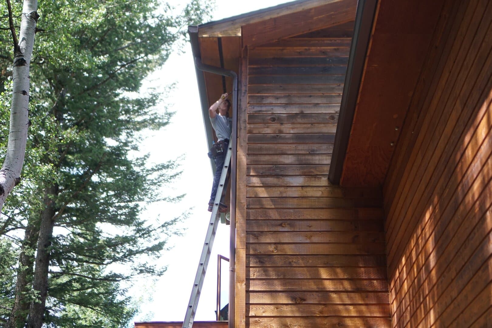 Green Brothers Gutters crew installing replacement seamless gutters on a Colorado mountain cabin